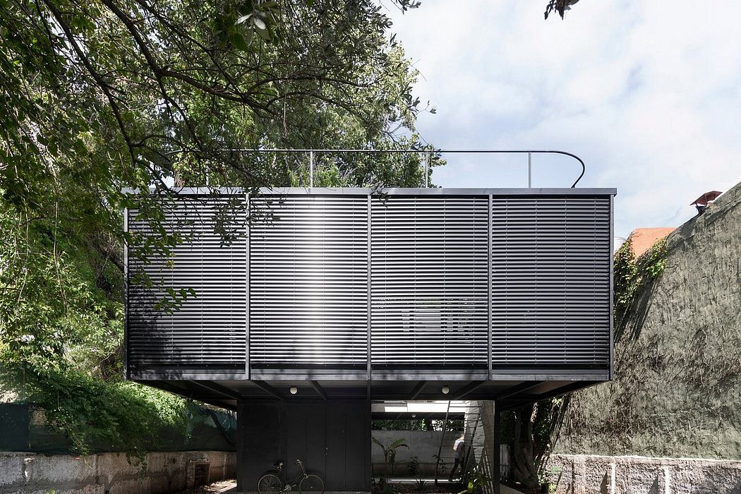 Contemporary house with metal facade elevated above a pool and terrace area, surrounded by