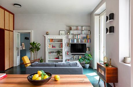 Modern living room with sofa, bookshelves, and decorative plants.