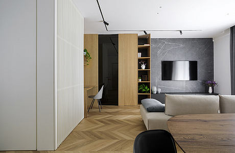 Modern living room with a herringbone wood floor, gray sofa, and marble