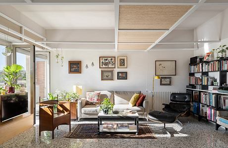 Contemporary living room with exposed beams, bookshelves, and cozy furnishings.