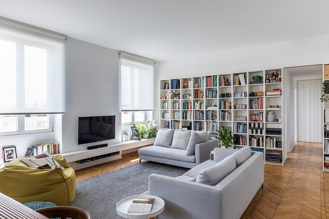 Modern living room with gray sofas, bookshelf, and hardwood floor.