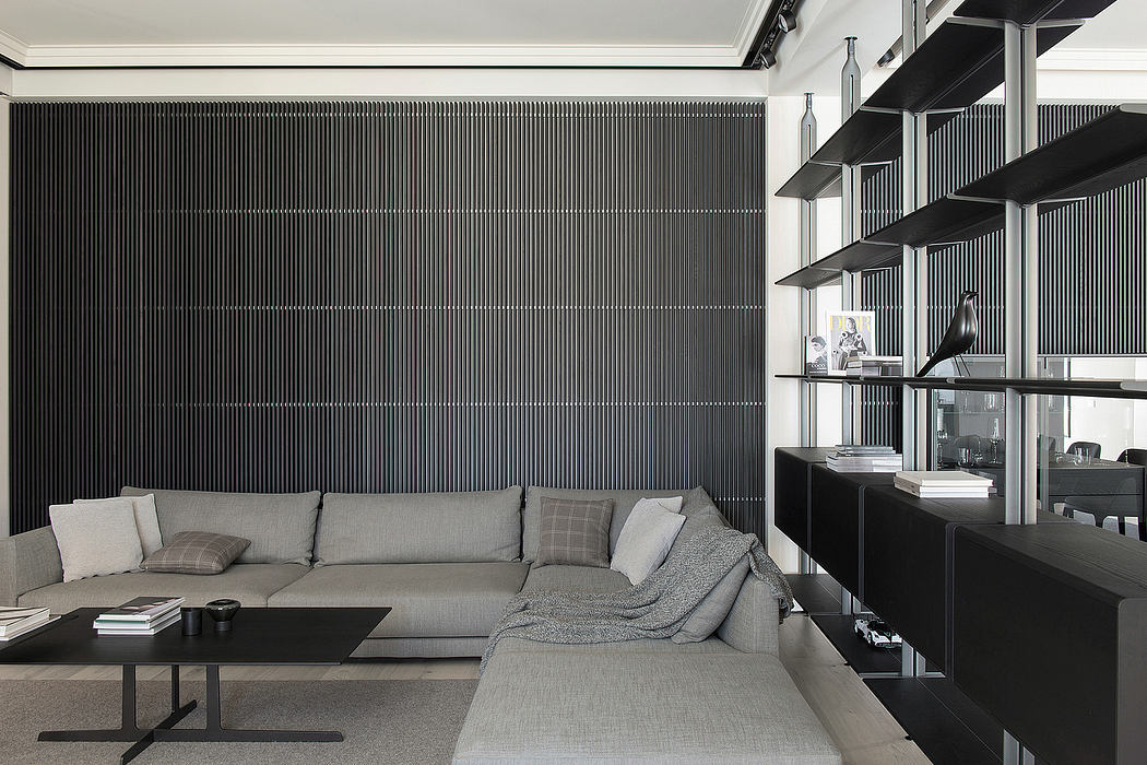 Modern living room with gray sectional sofa and black shelving units.