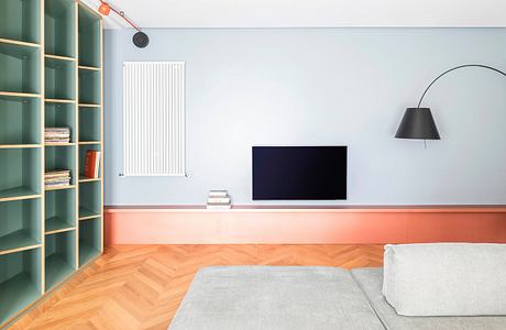 Minimalist living room with blue walls, bookshelf, TV, and gray sofa