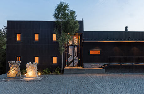 Modern black house with lit windows at dusk.