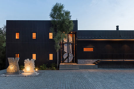 Modern black house with lit windows at dusk.