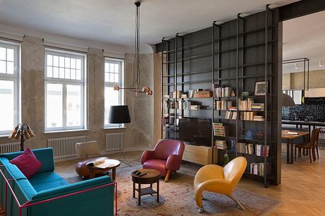 Modern living room with colorful furniture and a large bookshelf.