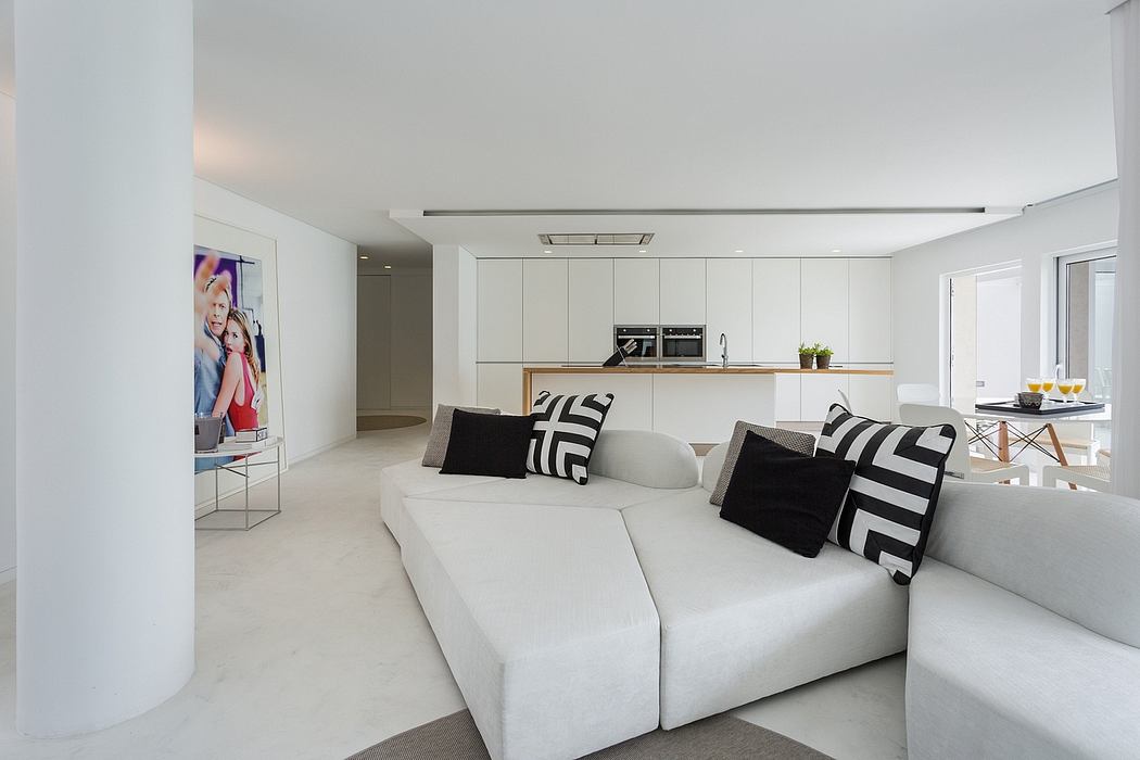 Contemporary interior with white sectional sofa, kitchenette, and colorful art.