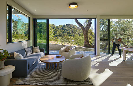 Modern living room with large windows and nature view.