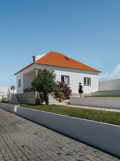 White house with orange roof and a person outside.