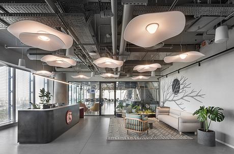 Contemporary office lobby with unique oval lighting and industrial ceiling.