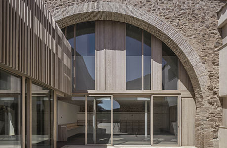 Contemporary stone building with large glass windows and wooden accents.