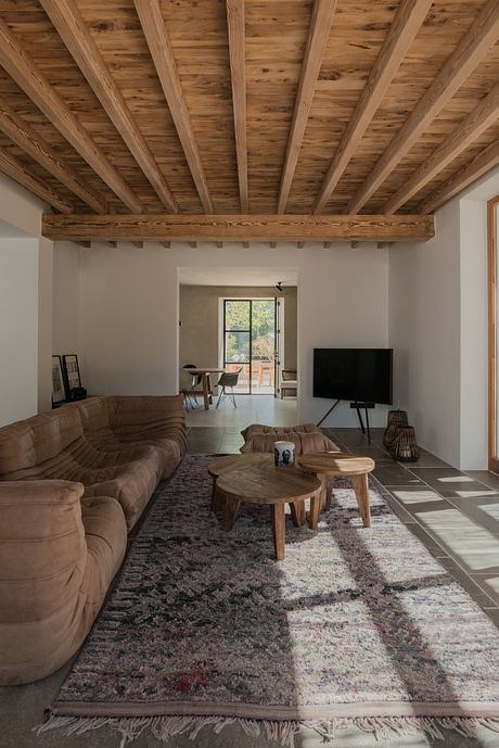 Rustic living room with exposed wooden beams, sectional sofa, and patterned