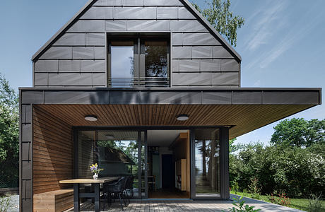 Contemporary A-frame house with contrasting siding and open patio.