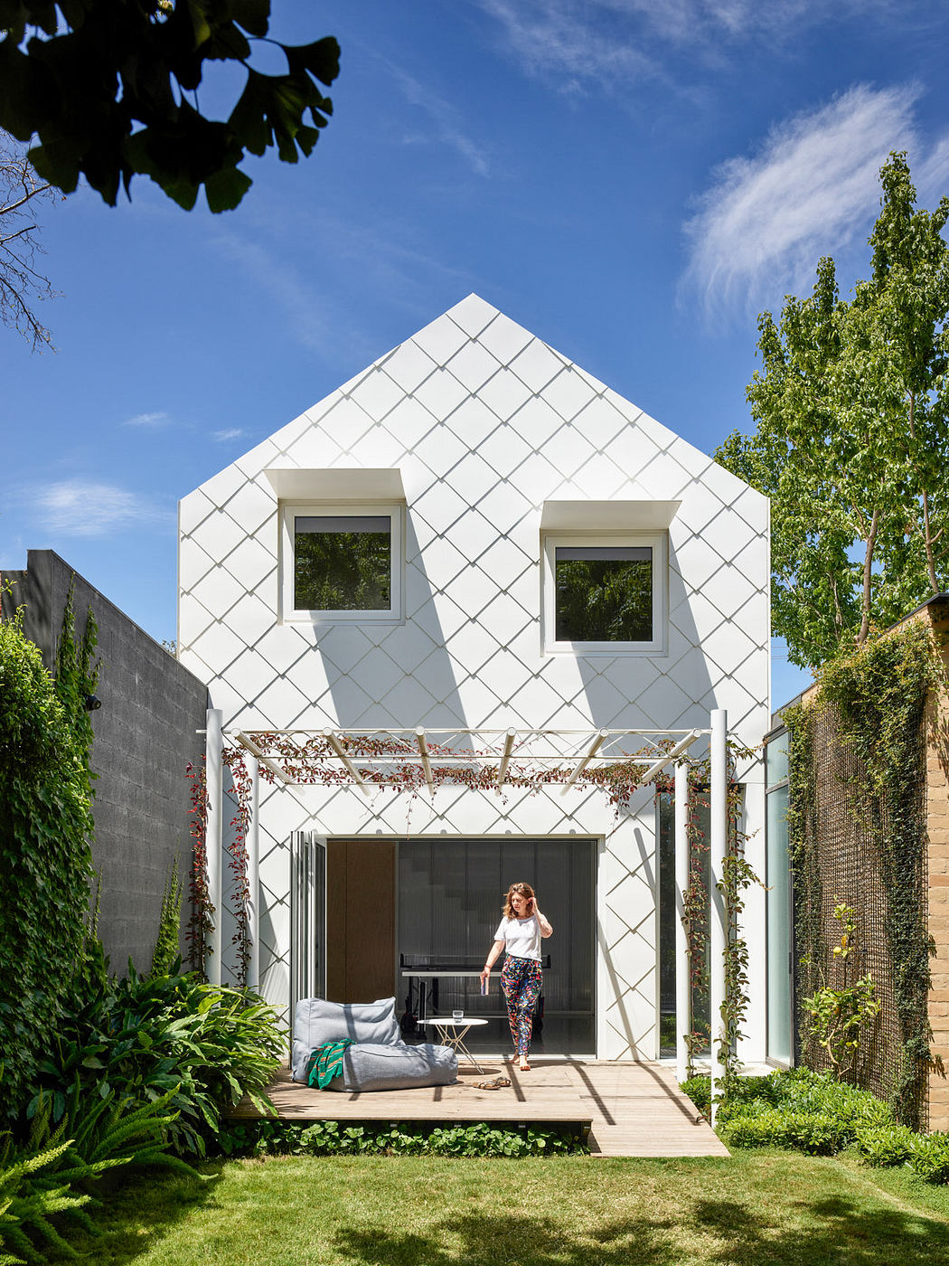 Modern house with geometric design and a woman on the porch.