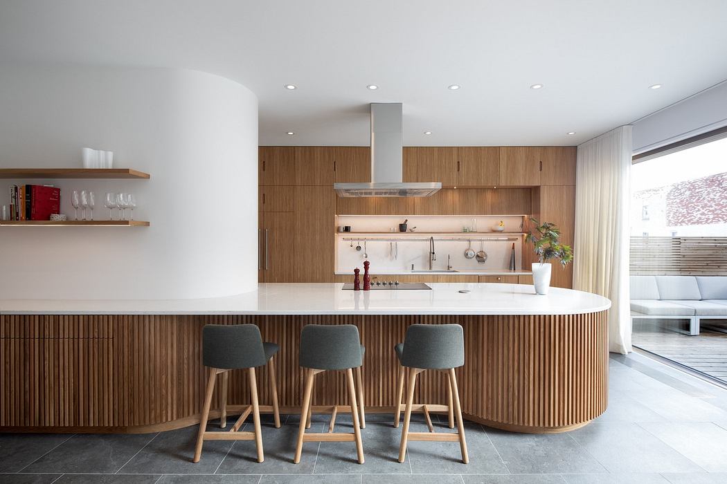 Modern kitchen interior with wooden finishes and bar stools.