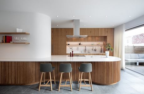 Modern kitchen interior with wooden finishes and bar stools.