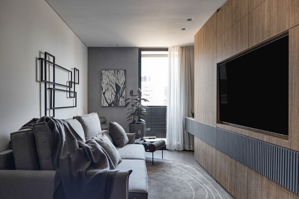 Modern living room with gray sofa, wooden cabinets, and wall-mounted TV.