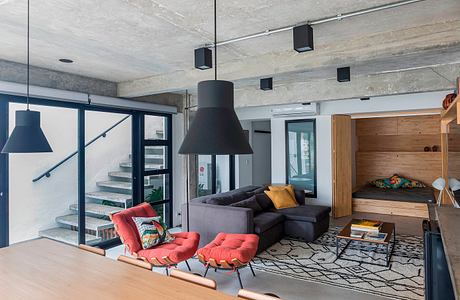 Contemporary living space with red chairs, a gray sofa, and large pendant lights