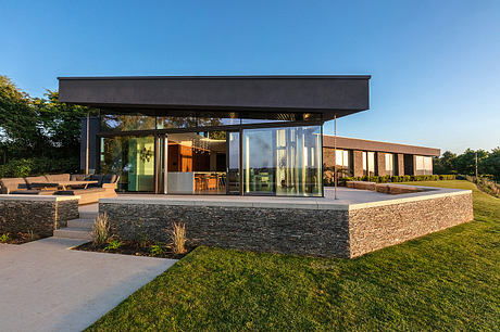 Modern house with large glass windows and flat roof at dusk.