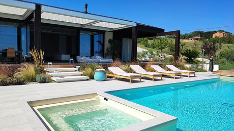 Modern house with poolside loungers and a hot tub.