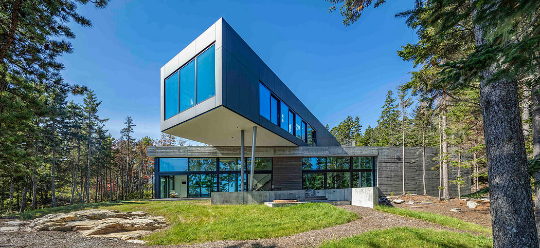 Cantilevered house with expansive glass windows amidst forest.