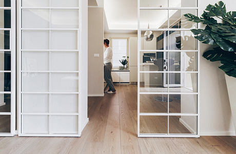 Modern home interior with glass doors and a person walking in the hallway.