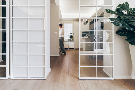 Modern home interior with glass doors and a person walking in the hallway.