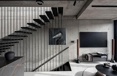 Modern living room with concrete walls and floating staircase design.