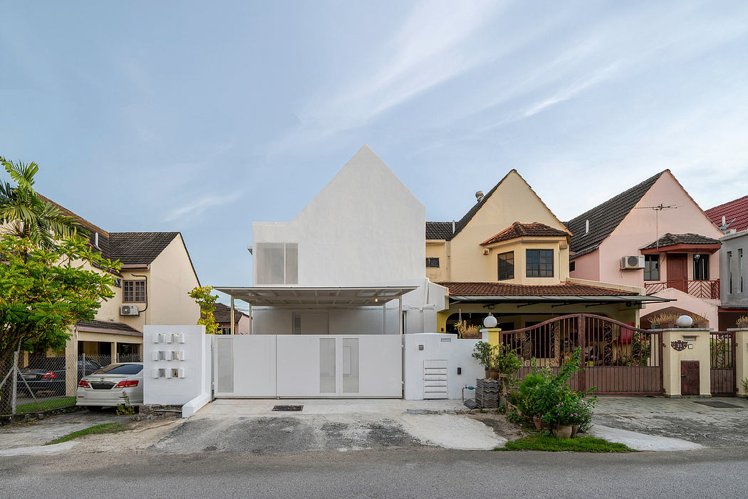 Minimalist white house with a geometric design, flanked by traditional homes.