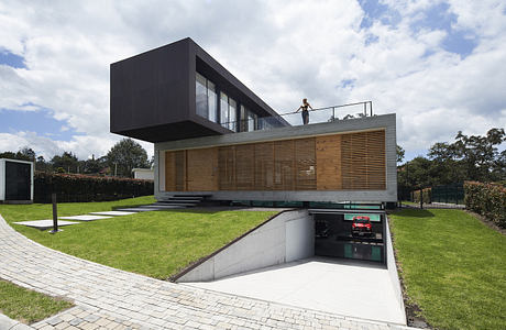 Modern two-story house with cantilevered upper floor and lawn.