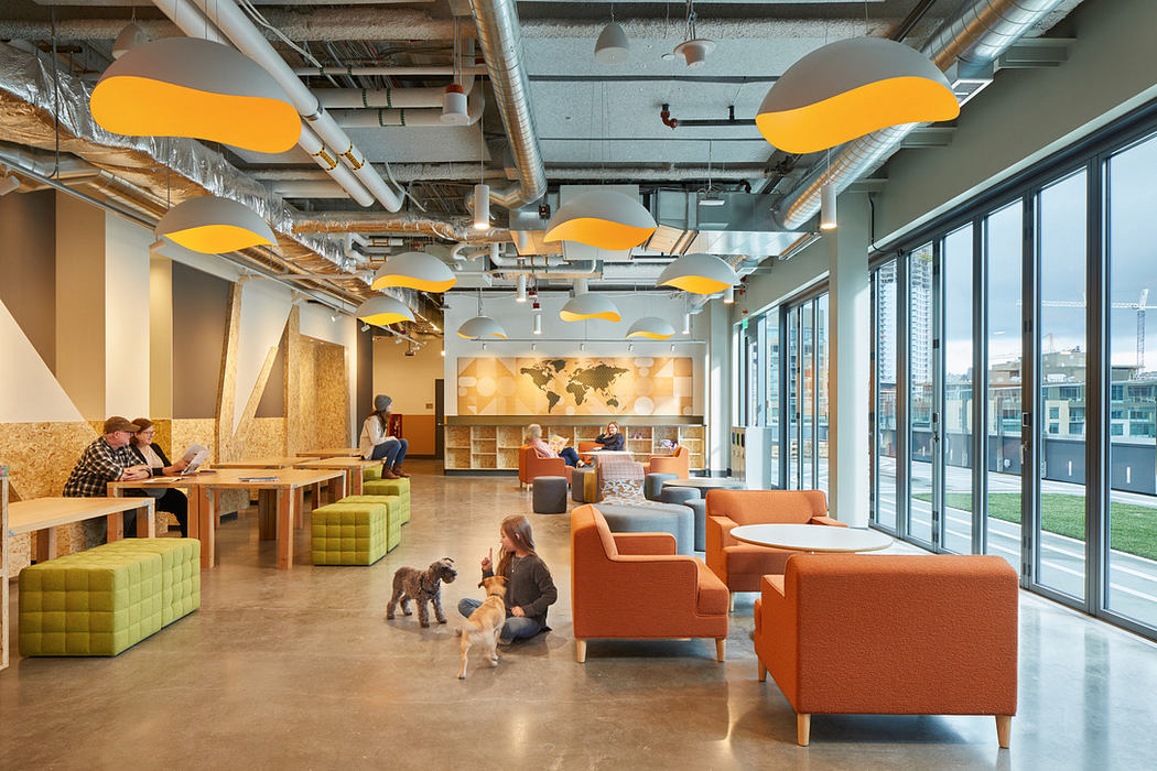 Contemporary office space with vibrant furniture and yellow cloud-like ceiling fixtures.