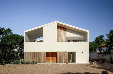 Modern two-story white house with large windows and wooden details.