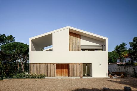 Modern two-story white house with large windows and wooden details.