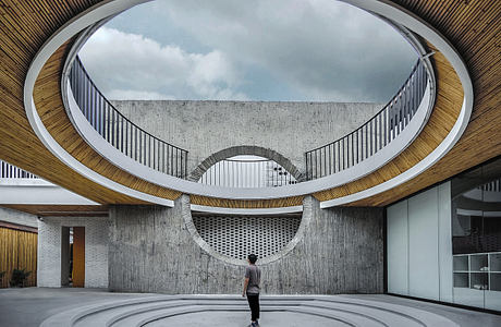 Modern interior courtyard with circular walkways and a person standing center.