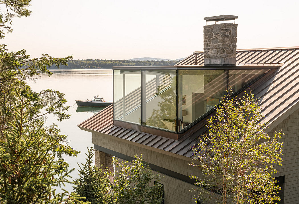 Lakeside house with large windows and a chimney, overlooking a boat on the