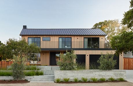 Modern two-story house with a metal roof and wooden siding.