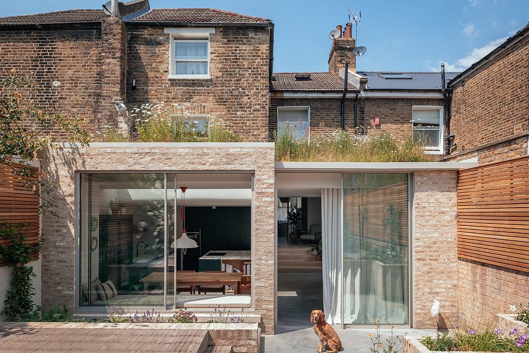 Contemporary brick extension with large glass windows and a dog sitting outside.