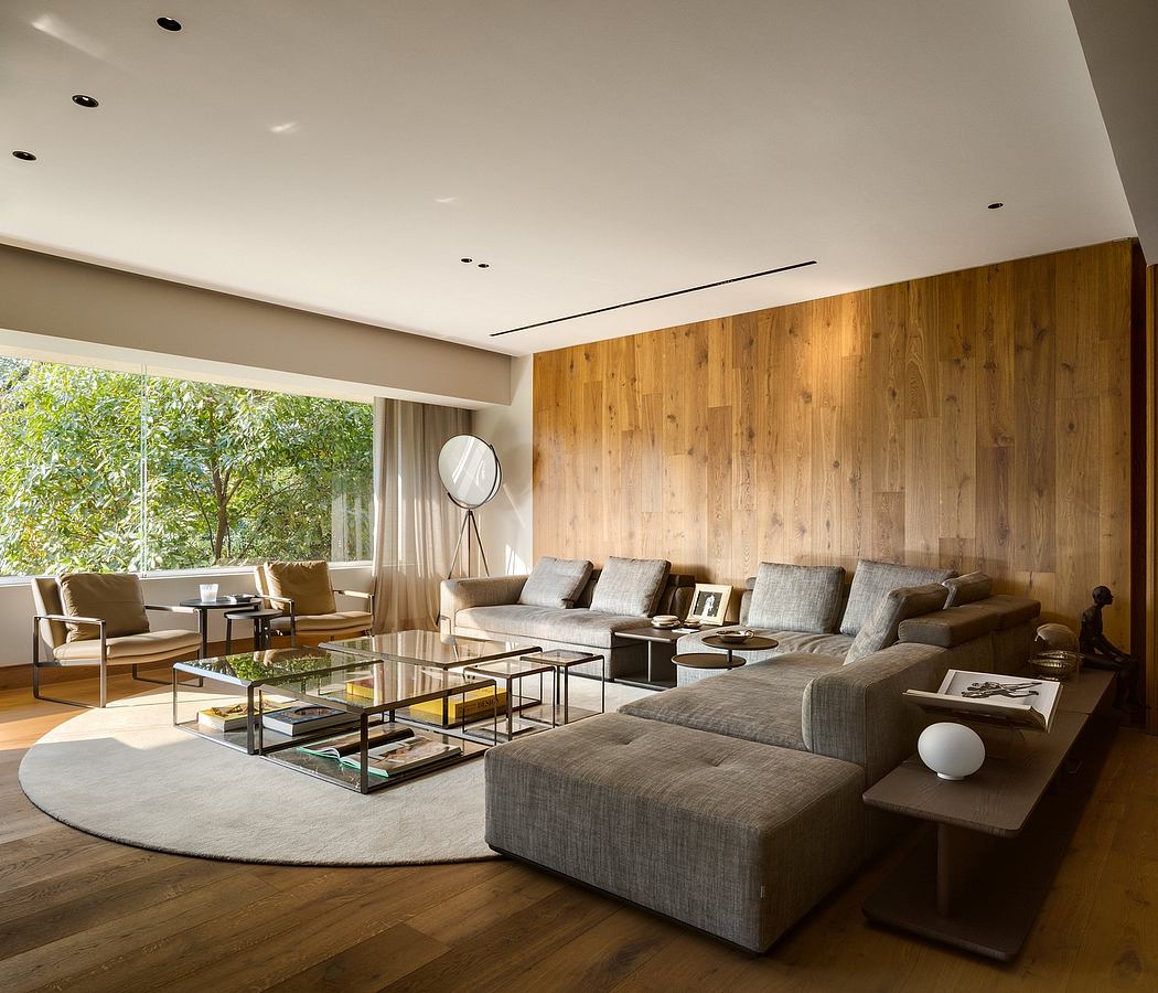 Elegant living room with wood paneling and large windows overlooking greenery.