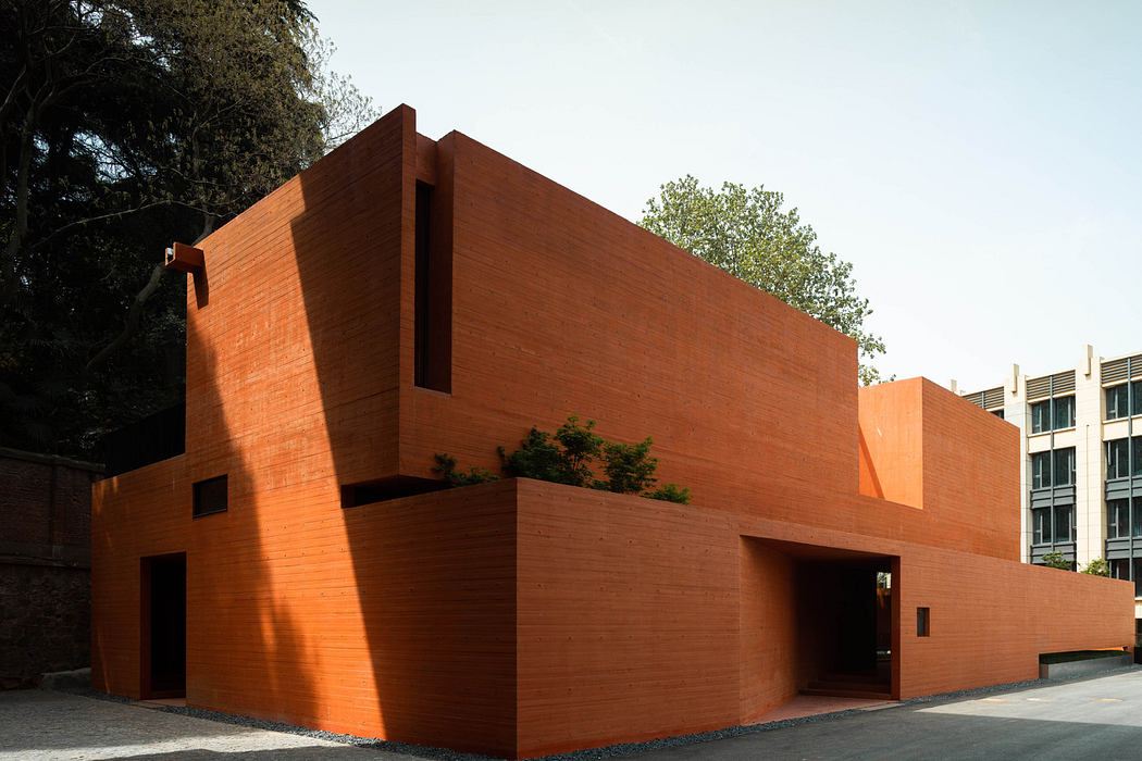 Modern terracotta brick building with geometric design and shadows.
