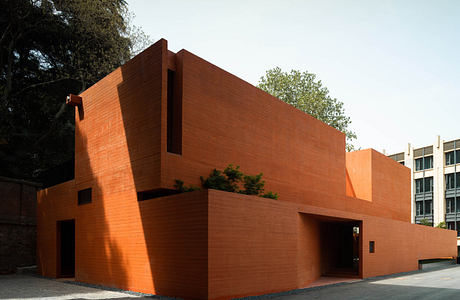 Modern terracotta brick building with geometric design and shadows.