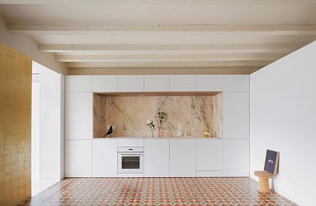 Minimalist kitchen with marble backsplash and patterned tile floor.