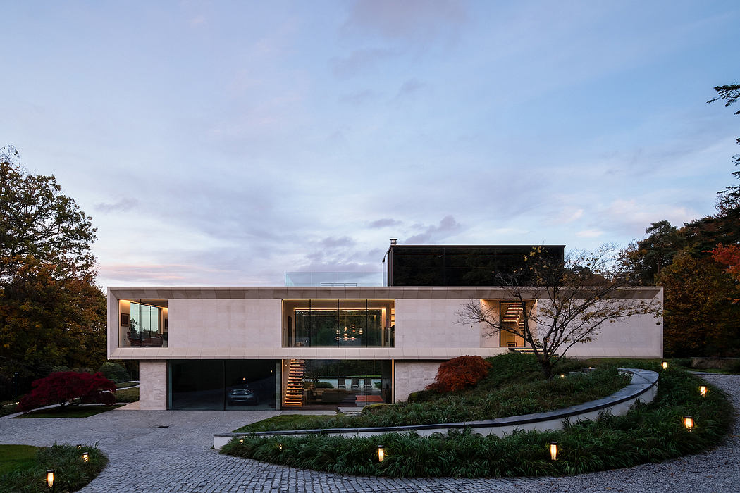 Contemporary house with large windows amid landscaped garden at dusk.