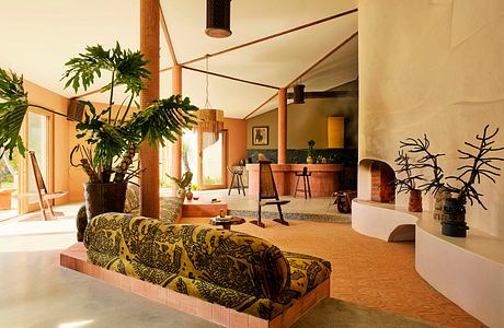 Contemporary room with earth tones, patterned sofa, and indoor plants.