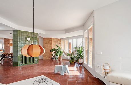 Contemporary living space with orange pendant lamp and green tile accents.