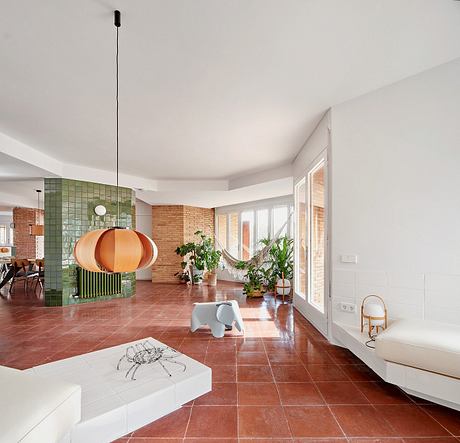 Contemporary living space with orange pendant lamp and green tile accents.