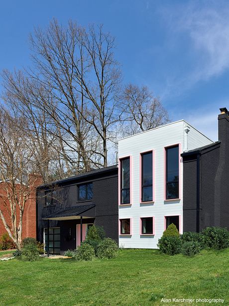 Modern two-story house with black and white exterior and pink accents.