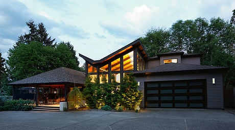 Contemporary house with illuminated windows at dusk and a double garage.