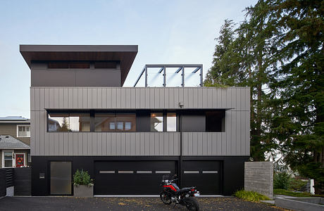 Modern two-story house with large windows and a motorcycle parked outside.