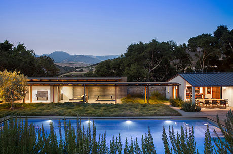 Contemporary house with pool at dusk, surrounded by nature.