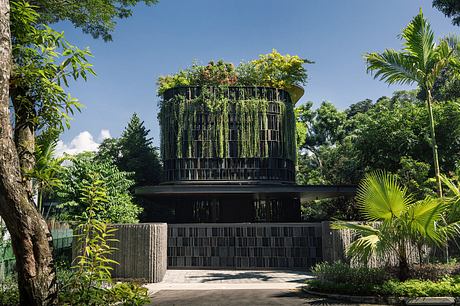 Modern building with lush rooftop garden surrounded by trees.